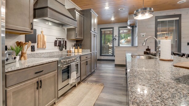 A modern kitchen with granite countertops, stainless steel appliances, and wooden cabinetry.