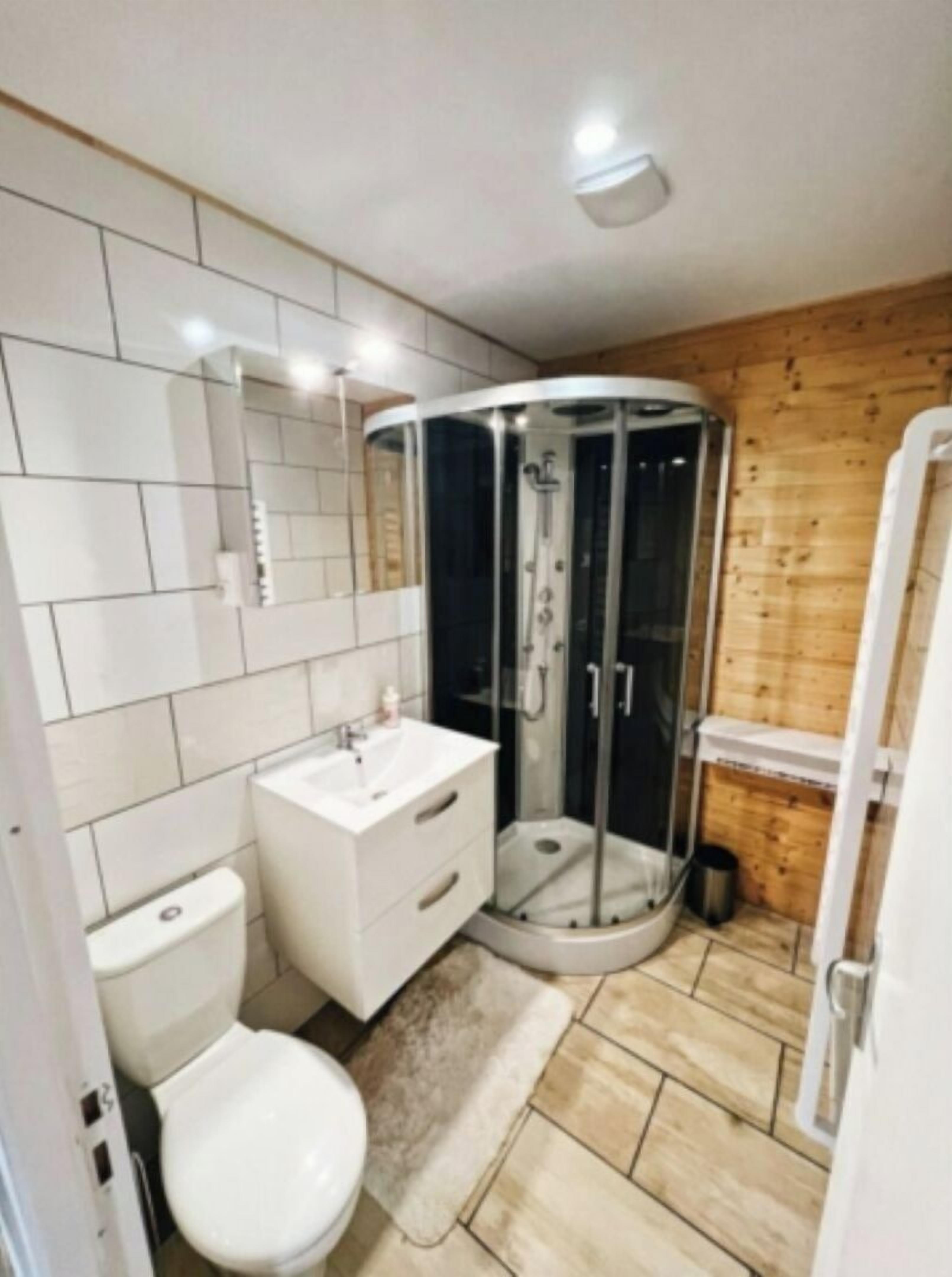 Une salle de bain moderne équipée de toilettes, d’un lavabo et d’une douche à parois de verre.