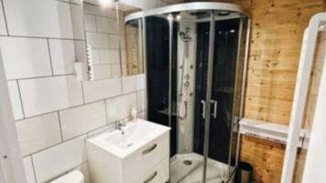 Une salle de bain moderne équipée de toilettes, d’un lavabo et d’une douche à parois de verre.