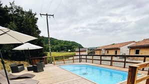 A wooden deck with a swimming pool, lounge chairs, and umbrellas. - . Quiet cottages (Prat-Bonrepaux)