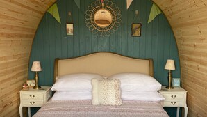 Une chambre confortable avec un lit, deux tables de chevet et un miroir décoratif au mur.