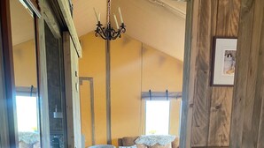 Un salon chaleureux avec un plancher en bois, un canapé en cuir marron, un tapis à rayures et un lustre.