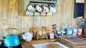 Une cuisine avec des murs en bois, un évier, une cuisinière et divers ustensiles et plats de cuisine.