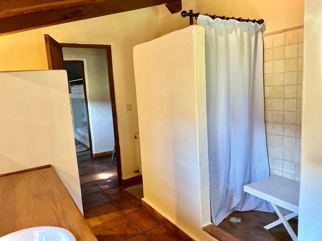 A bathroom with a shower curtain, a small table, and a tiled floor.