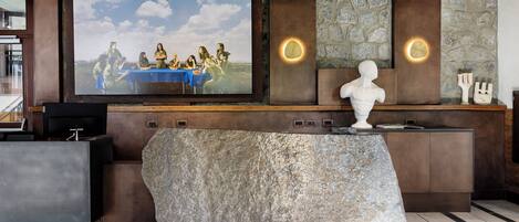 A reception area with a large flat-screen TV, a stone accent piece, and a modern console.