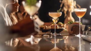Eine Bar mit zwei Martini-Gläsern, einer Flasche und einer kleinen Schale mit Speisen.