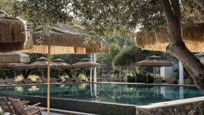 A pool area with lounge chairs and thatched umbrellas. - Pereh Mountain Resort  (Katzrin)