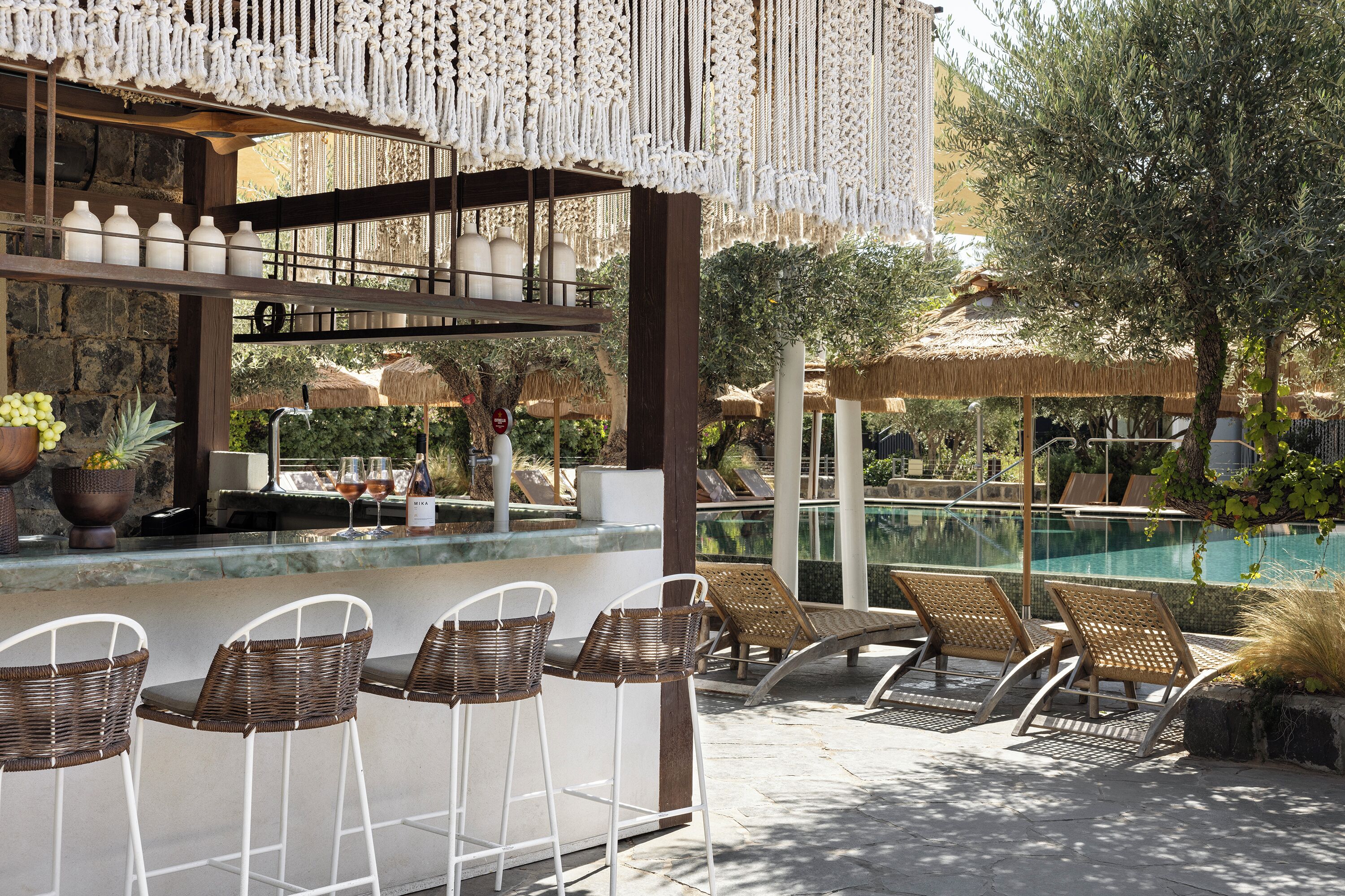 A poolside bar area with wicker chairs, a bar counter, and a view of the pool.