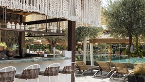 A poolside bar area with wicker chairs, a bar counter, and a view of the pool.