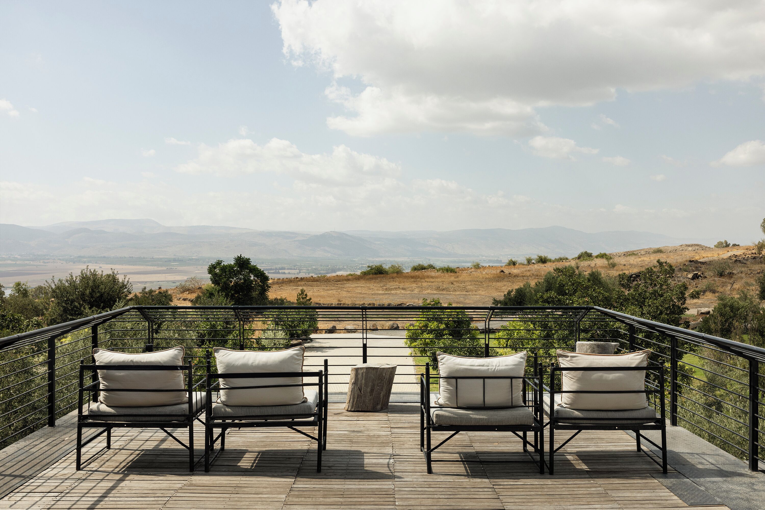 Eine Terrasse mit vier Stühlen und einem Tisch mit Blick auf eine hügelige Landschaft.