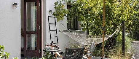 A hammock chair, a small table with a bottle and glasses, and a door to a room.
