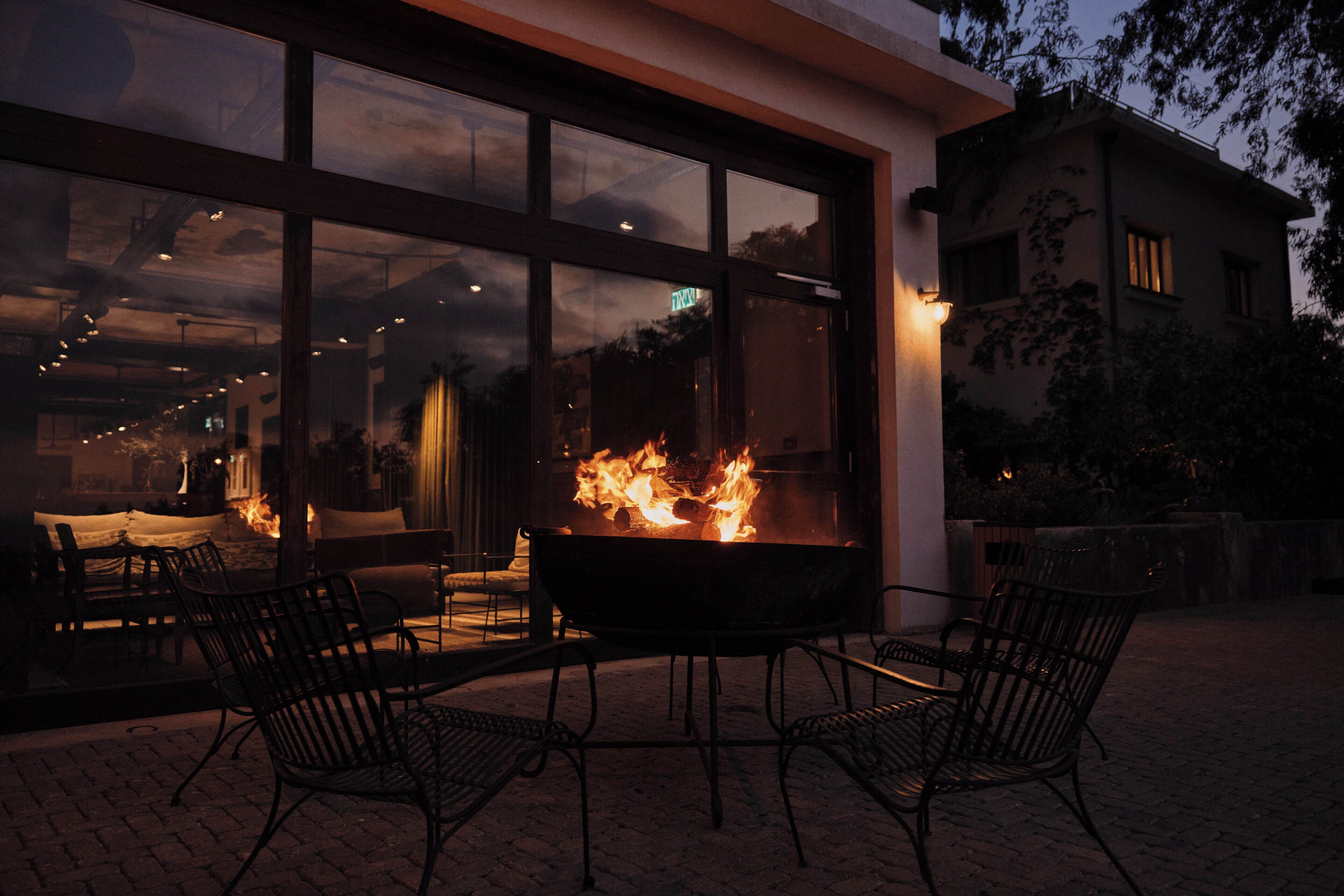 A patio with a fire feature, outdoor seating, and a view through large windows.