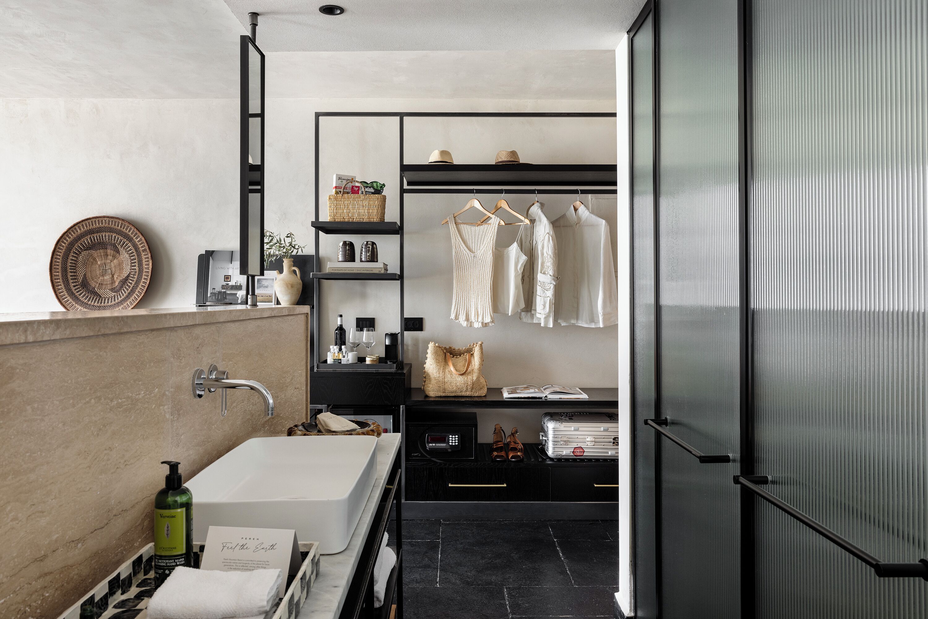 Um banheiro moderno com banheira, toucador e closet espaçoso com roupas penduradas.