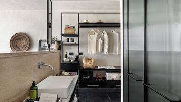 Um banheiro moderno com banheira, toucador e closet espaçoso com roupas penduradas.