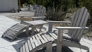 A wooden Adirondack chair and a matching lounge chair with a table in a patio area. - Villa Vitviken Sleeps 4 With Pool (Slite)