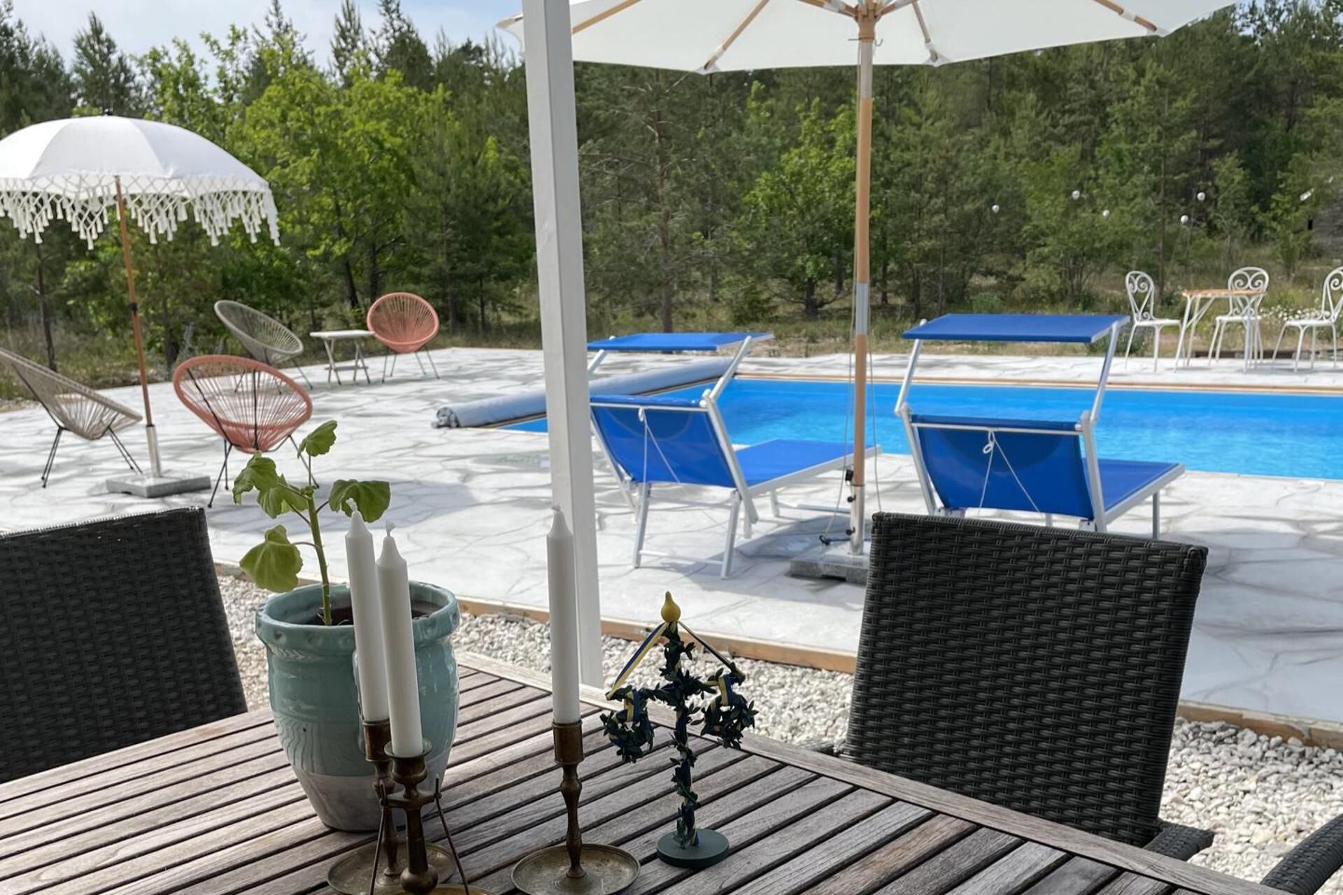 A poolside area with lounge chairs, a table with a candle, and a view of the pool.