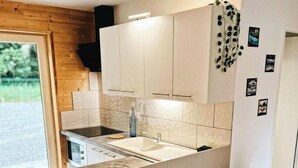 Una cocina moderna con una isla central, armarios blancos y encimera negra. Cuatro sillas blancas con patas de madera rodean la isla.