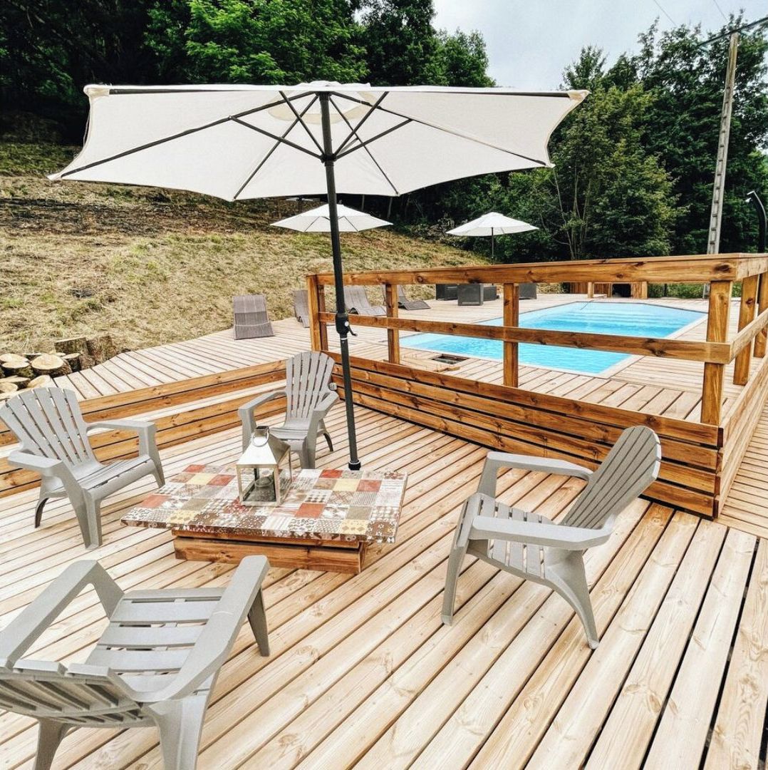 A wooden deck with a pool, outdoor seating, and umbrellas.