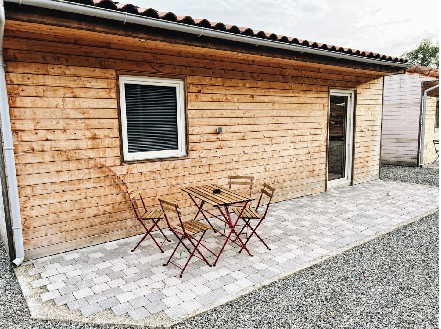 A wooden building with a tiled patio, a window, and a door.