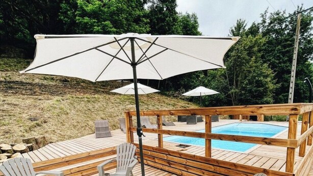A wooden deck with a pool, outdoor seating, and umbrellas.