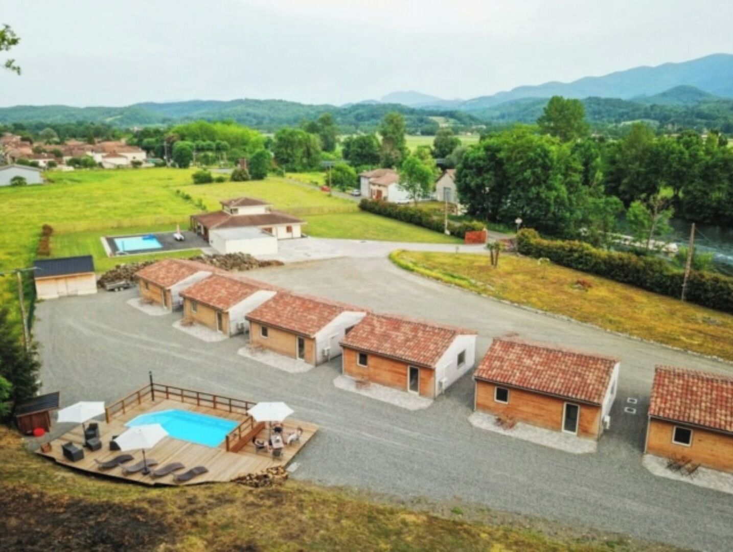 A residential area with multiple small houses, a swimming pool, and a paved driveway.