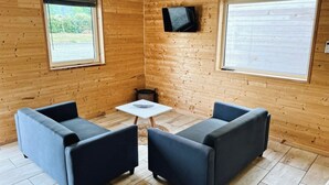 Ett mysigt rum med träväggar, två soffor, ett litet bord och en tv som är monterad på väggen.