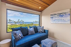 Una habitación con un ventanal que ofrece vistas a palmeras y al océano.