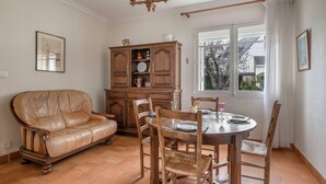 Un comedor con una mesa redonda, sillas de madera, un sofá de cuero y un armario de madera.