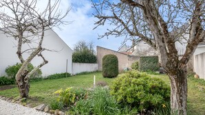 Un jardín con un sendero de grava, un estanque pequeño y diversas plantas.