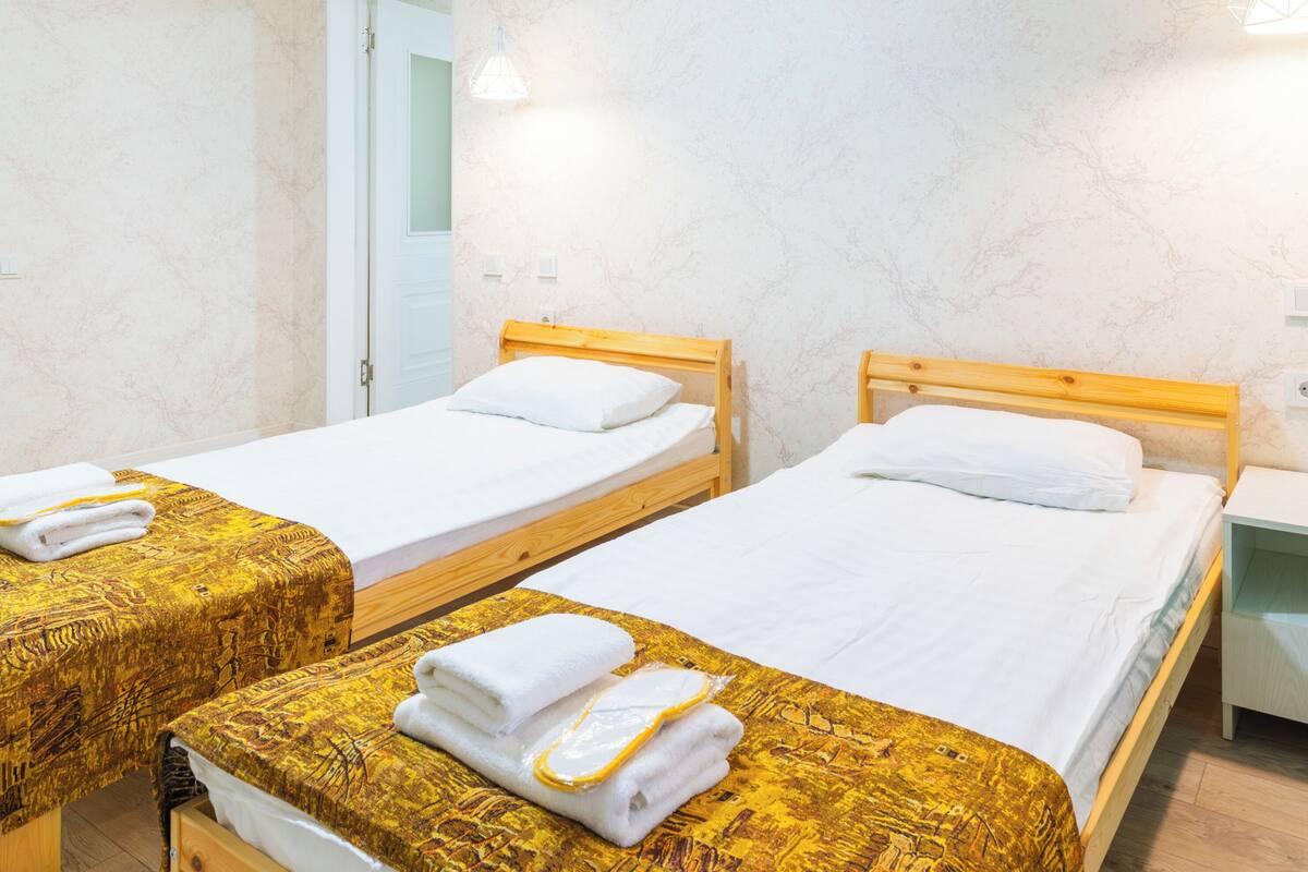 A hotel room with three single beds, wooden headboards, and white linens.