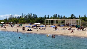 Uma praia com guarda-sóis, pessoas e uma área coberta.