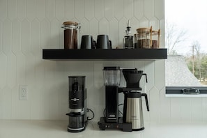 A kitchen with a coffee maker, a blender, and a coffee grinder on the counter.