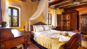 Une chambre à coucher de style traditionnel, avec un lit à baldaquin, des meubles en bois et un mur en pierre.