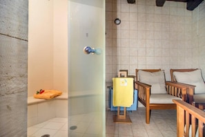 A bathroom with a shower, a bench, and a wooden chair with a cushion. - Orange Villa - Samonas - 1 Bedroom Maisonette (Apokoronas)