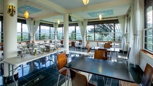 A spacious dining area with high ceilings, large windows, and a buffet setup. - THE CRESTED CRANE BWINDI HOTEL (Kyesero)