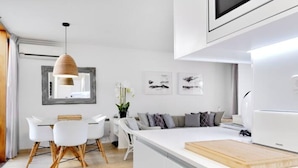 A modern kitchen with white cabinets, a wooden island, and a dining area with white chairs and a hanging light fixture. - Cosy, luxury 2-bed golf villa (La Manga Club) (Cartagena)