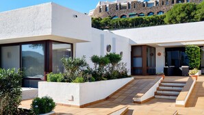 A modern building with a courtyard, featuring a staircase leading to a covered area with seating. - Cosy, luxury 2-bed golf villa (La Manga Club) (Cartagena)