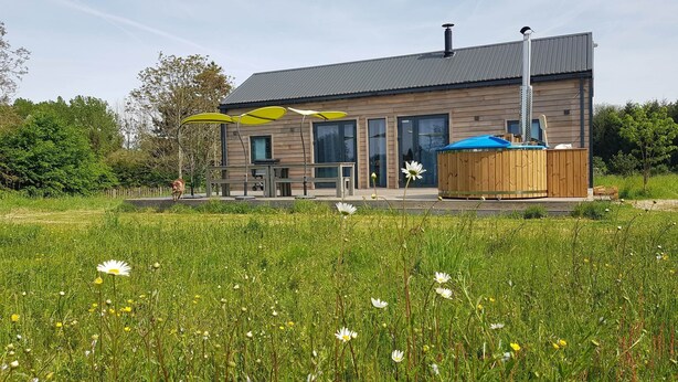 Une maison moderne dotée d’un patio, d’une terrasse en bois et d’un jacuzzi.