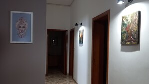 A hallway with stone flooring, wooden doors, and wall-mounted artwork. - Vacation house, sleeps 6, in Noto 500 mt from the center. (Noto)