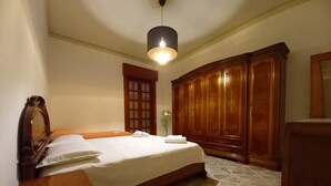 A bedroom with a large bed, wooden wardrobe, and a hanging light fixture. - Vacation house, sleeps 6, in Noto 500 mt from the center. (Noto)
