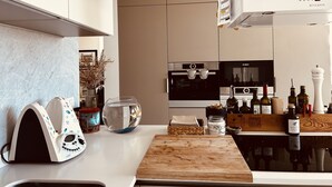 Et moderne køkken med en hvid bordplade, skærebræt i træ, Bosch ovn og et køleskab.
