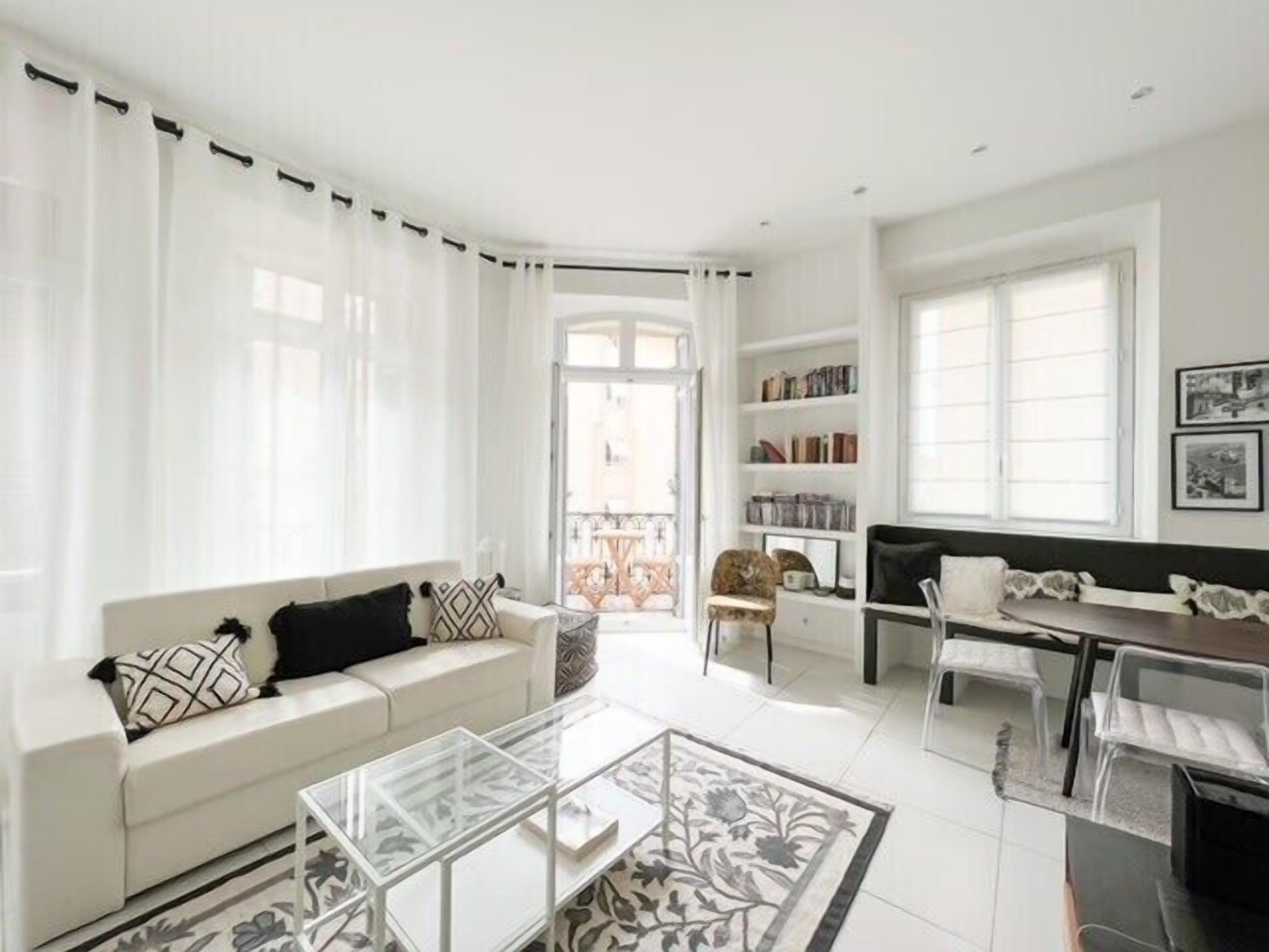 En moderne stue med en hvid sofa, et glasbord og en balkon med udsigt.