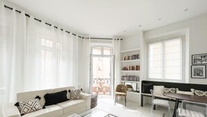 Ein modernes Wohnzimmer mit einem weißen Sofa, einem Glastisch und einem Balkon mit Blick.