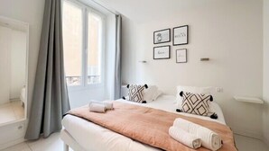 Ein modernes Schlafzimmer mit einem großen Bett, grauen Vorhängen und einem Fenster.