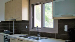 A modern kitchen with a built-in dishwasher, a double sink, and a window above the sink. - 3-room House With Sea View (Ierapetra)