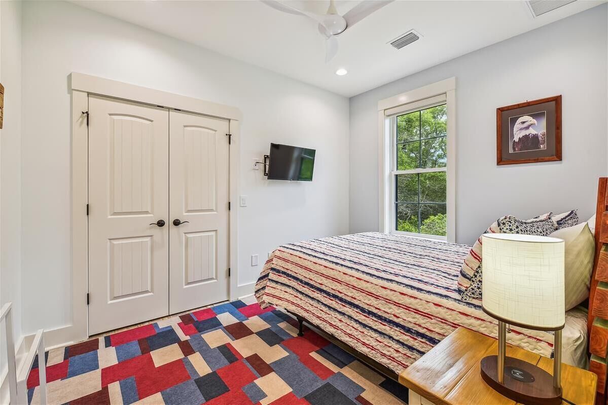 Une chambre à coucher avec un lit, une télévision, une fenêtre et une porte.