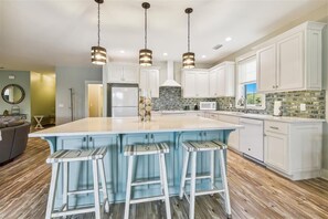 A spacious kitchen with a large island, white cabinetry, and a tiled backsplash. - Welcome to Boomerang! (St. George Island)