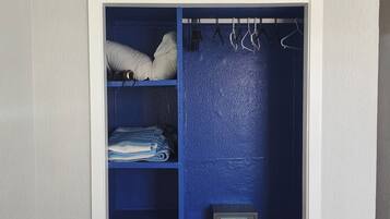 A walk-in closet with a white door, blue shelving, and a safe.