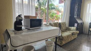 Une chambre équipée d’une table, d’un four à micro-ondes, d’une machine à café, d’un canapé, d’une poubelle et offrant une vue sur l’extérieur.