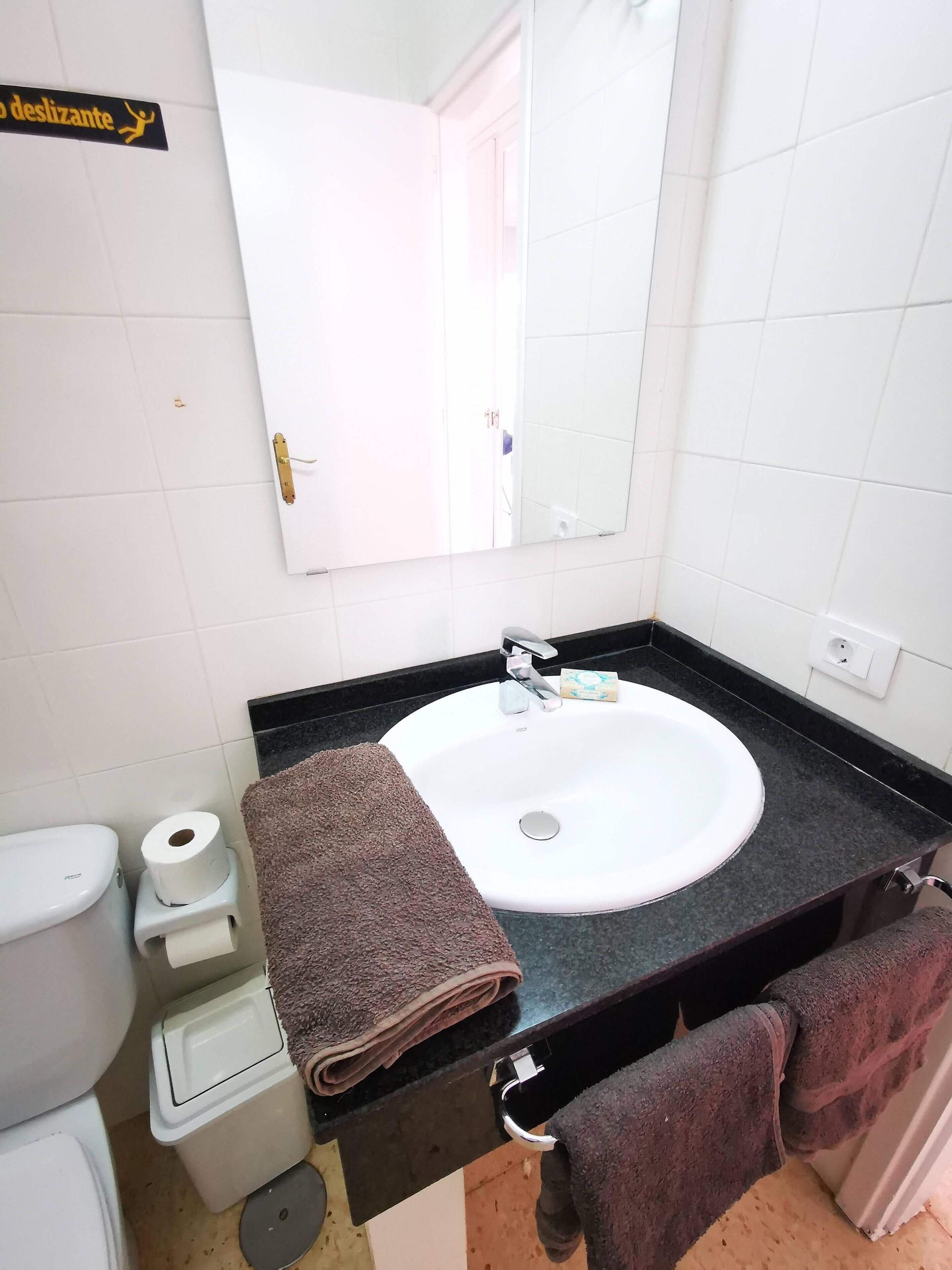 A bathroom with a white sink, a mirror, a towel rack, and a toilet.